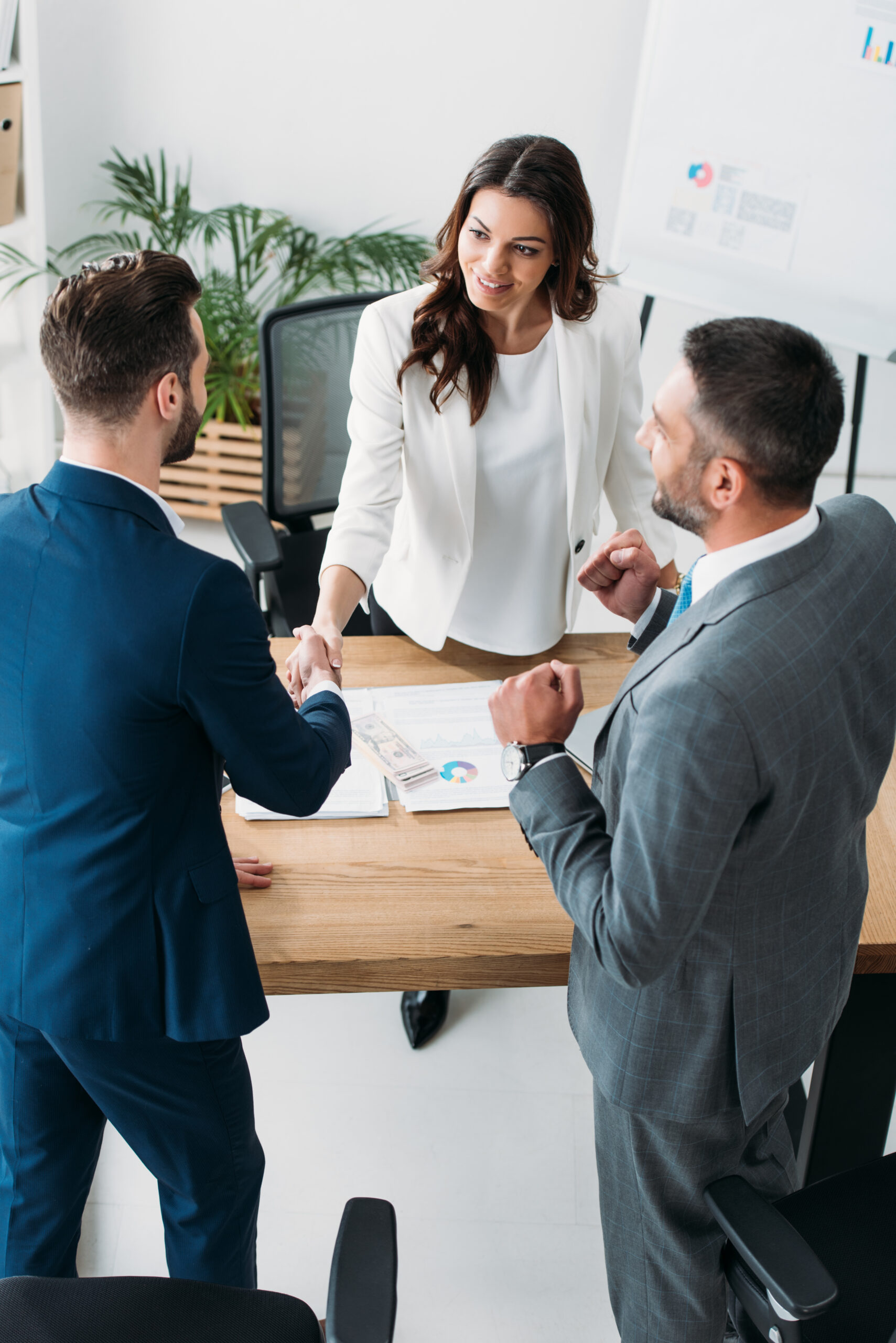 beautiful advisor and handsome investor shaking hands at workplace